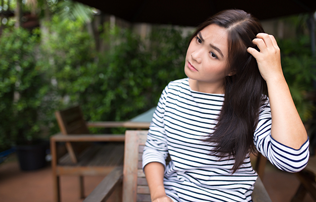 A woman scratching her scalp.