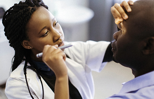 An eye doctor shining a flashlight into a patient's eye.