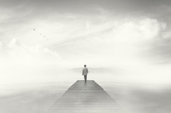 Dream-like photo of man reaching the end of a boardwalk in heavy fog