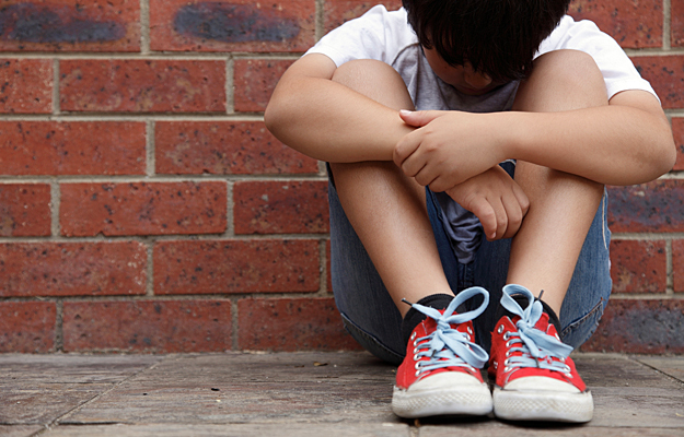 A young boy sitting with his head down.