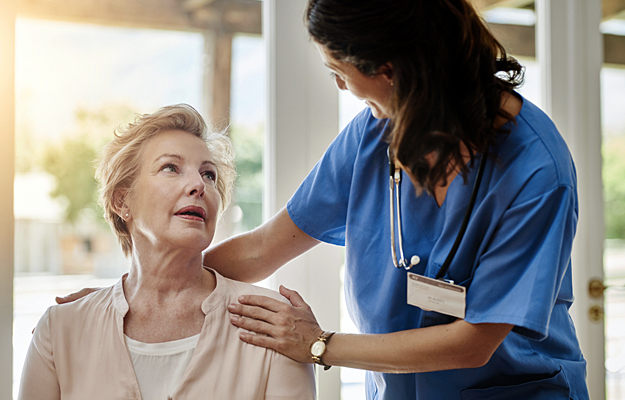 A nurse smiling as she talks to a patient.