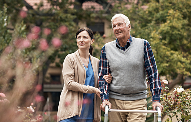 A senior man and caregiver walking outside.