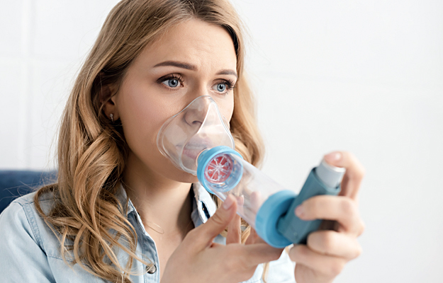 A woman using an inhaler with a spacer.