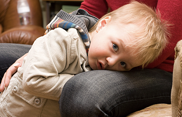 A young boy hiding between a parent's knees.
