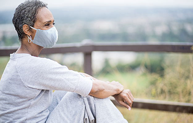 A senior woman wearing a cloth face mask outside.