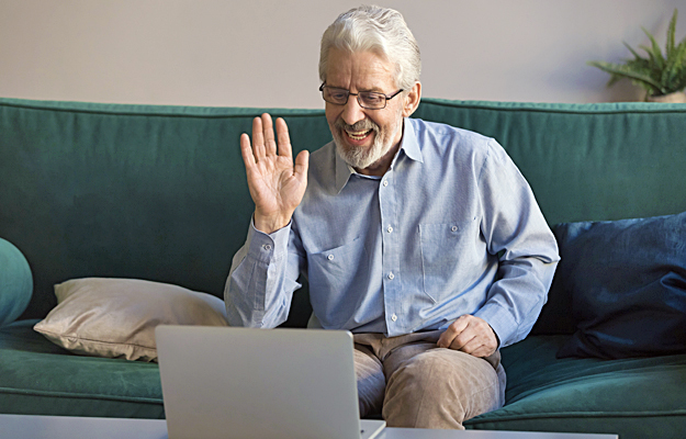 A senior man video chatting on a laptop.