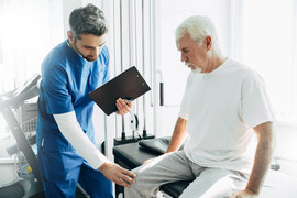 Health professional examining senior man's knee