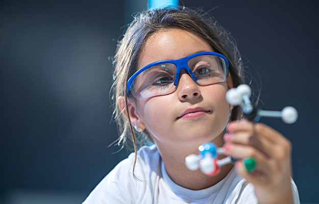 A young girl examining a molecular model.
