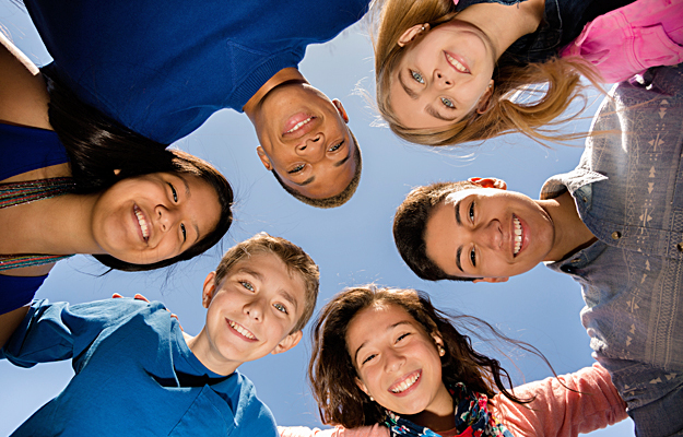 A diverse group of teenagers huddling together.