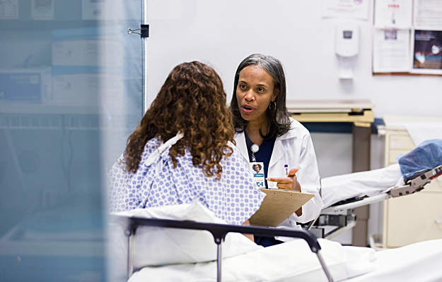 A female patient in a hospital bed talking to a doctor.