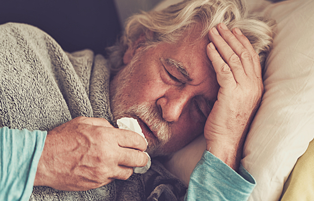 A senior man with the flu lying in bed.