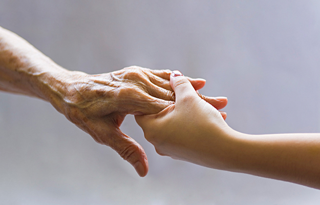An elderly person's hand holding a young person's hand.
