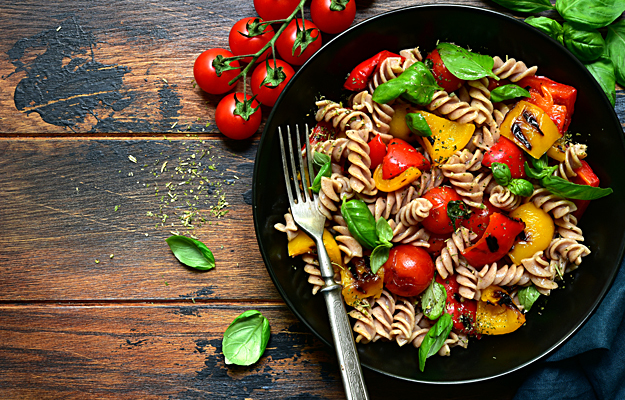 A bowl of pasta and grilled vegetables.