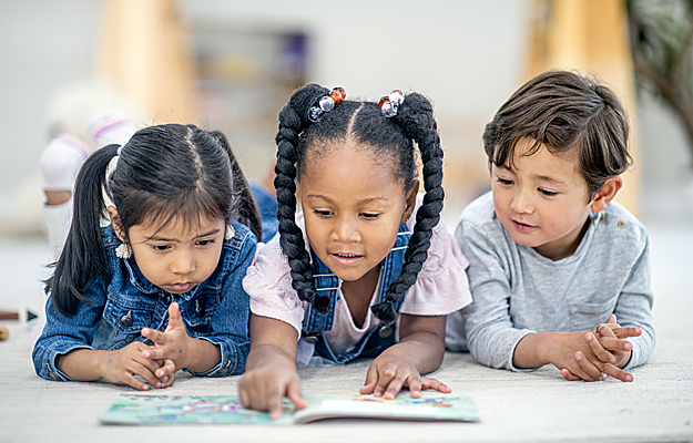 Three children reading a book together.