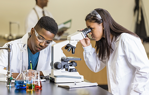 High school students using a microscope and examining slides.