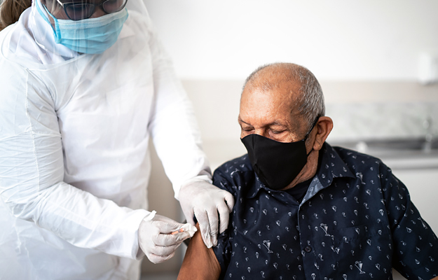 A senior man receiving a vaccine in his arm.