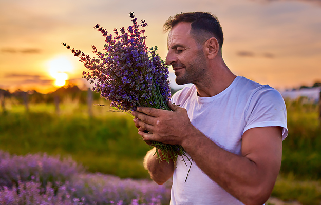 A man smelling a bundle of lavender.