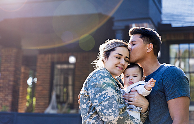 A woman in a military uniform with her husband and their baby. 