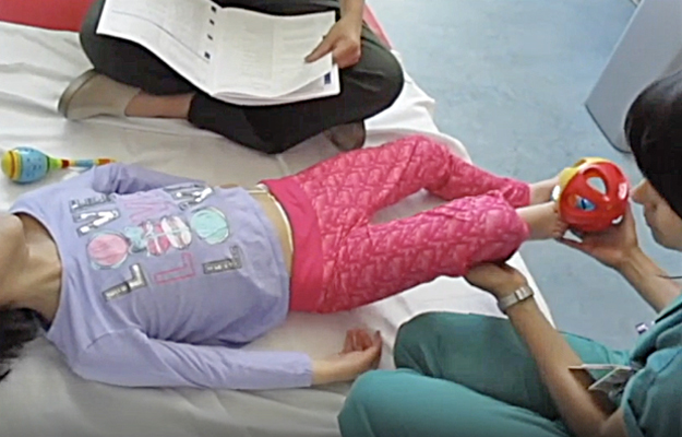 A therapist doing physical therapy with a child affected by AADC.