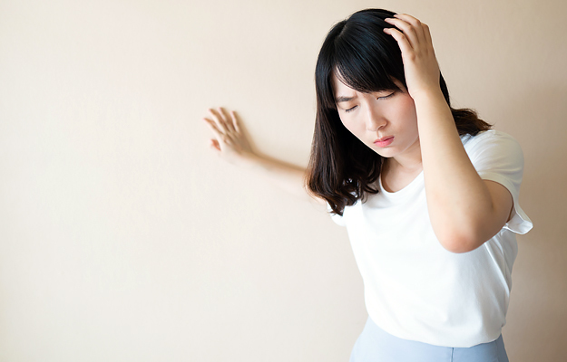 A young woman feeling dizzy and losing her balance.