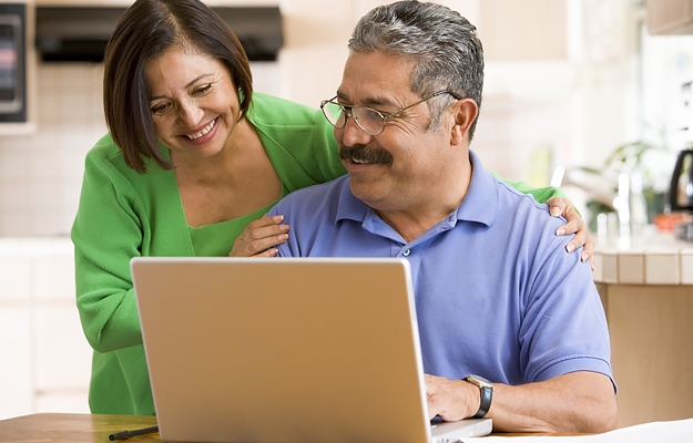 A senior Hispanic couple looking at a laptop.