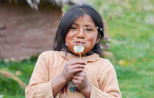 A Native American girl blowing a dandelion.