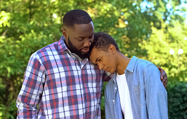 A man comforting a teenage boy.