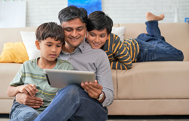 A man and his two young sons looking at a digital tablet.