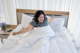 Woman stretching in bed after waking up