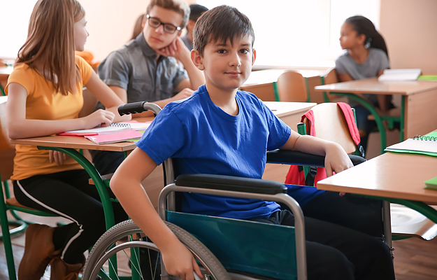 A teenage boy in a wheelchair at school with classmates.