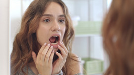 Woman checking the inside of her mouth in a mirror