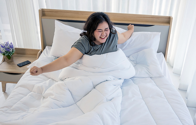 A woman stretching in bed after waking up.