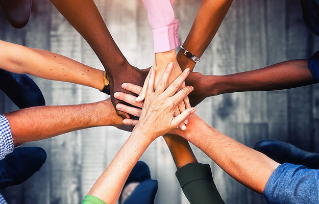 A close-up of a diverse group of people's hands together.