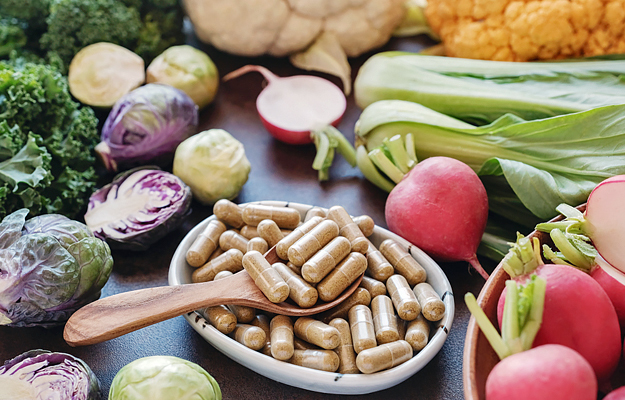 Fiber capsules in a bowl surrounded by fibrous vegetables.