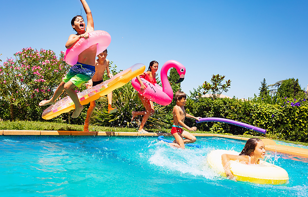 Kids jumping into a swimming pool with inflatable tubes.
