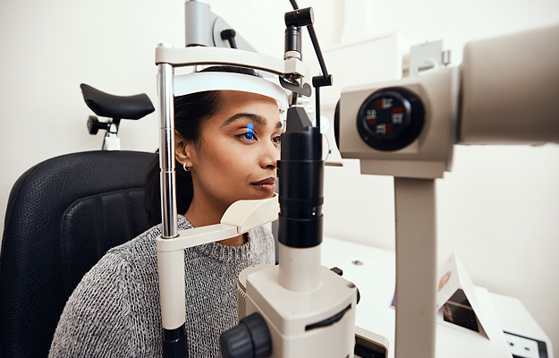 A woman getting her eyes examined with a slit lamp.