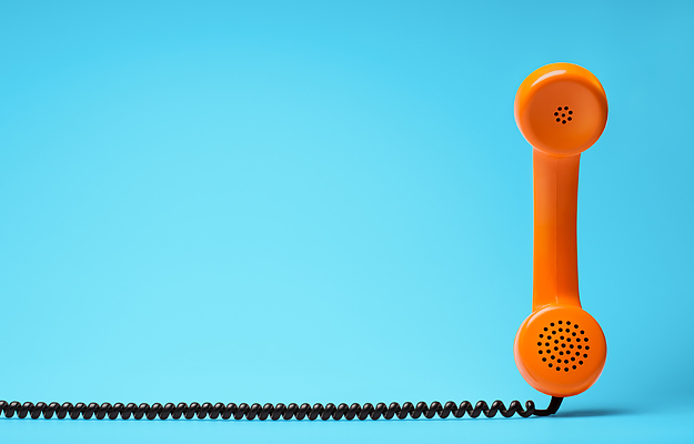 An orange telephone with a black coil cord on a blue background.