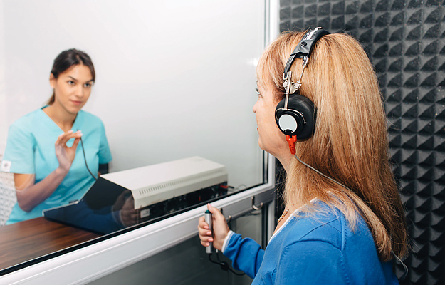 An audiologist doing a hearing exam on a mature woman.
