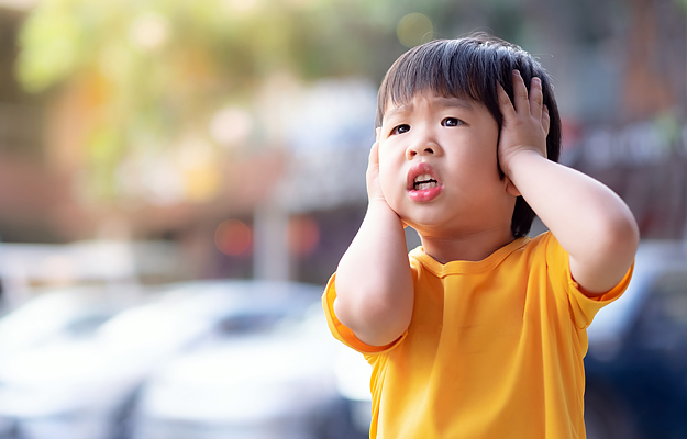 A young boy covering his ears.