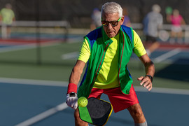 Senior man hitting a pickleball with paddle