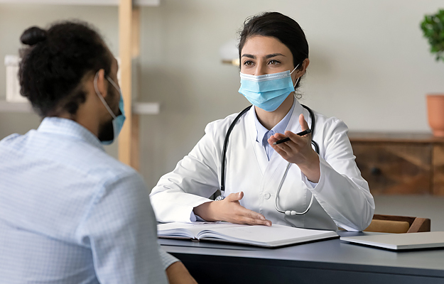 A masked doctor talking to a masked patient.