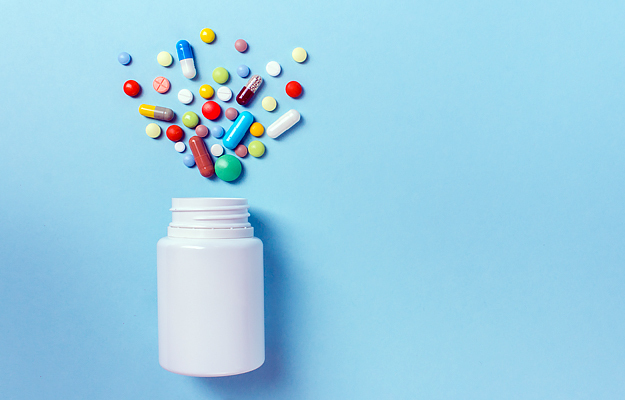An assortment of pills spilling out of a medicine bottle.