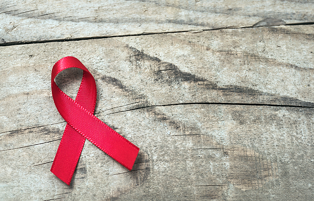 A red awareness ribbon on top of a wooden background.