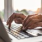 A pair of hands typing on a laptop