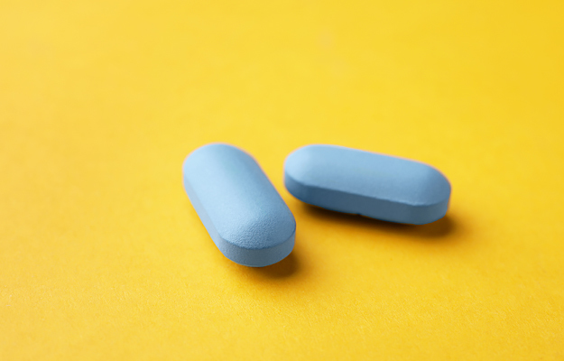 Two identical looking blue pills on a yellow background.