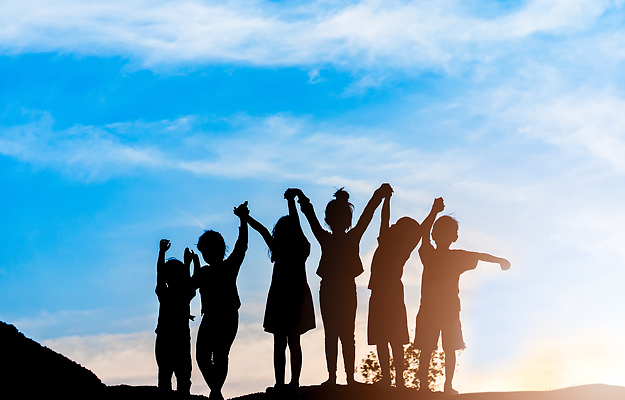 A silhouette of six children holding hands with their arms raised.