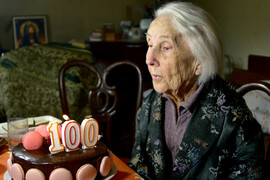 Woman blowing out one hundred candle on her birthday cake.