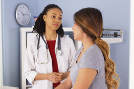 Doctor talking to young female patient in exam room.