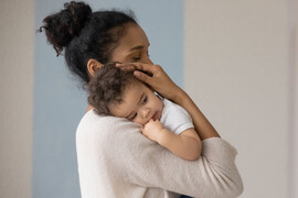 Mother holding infant against chest.