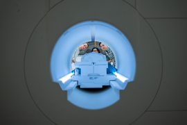 View through an fMRI scanner as three researchers peer inside.